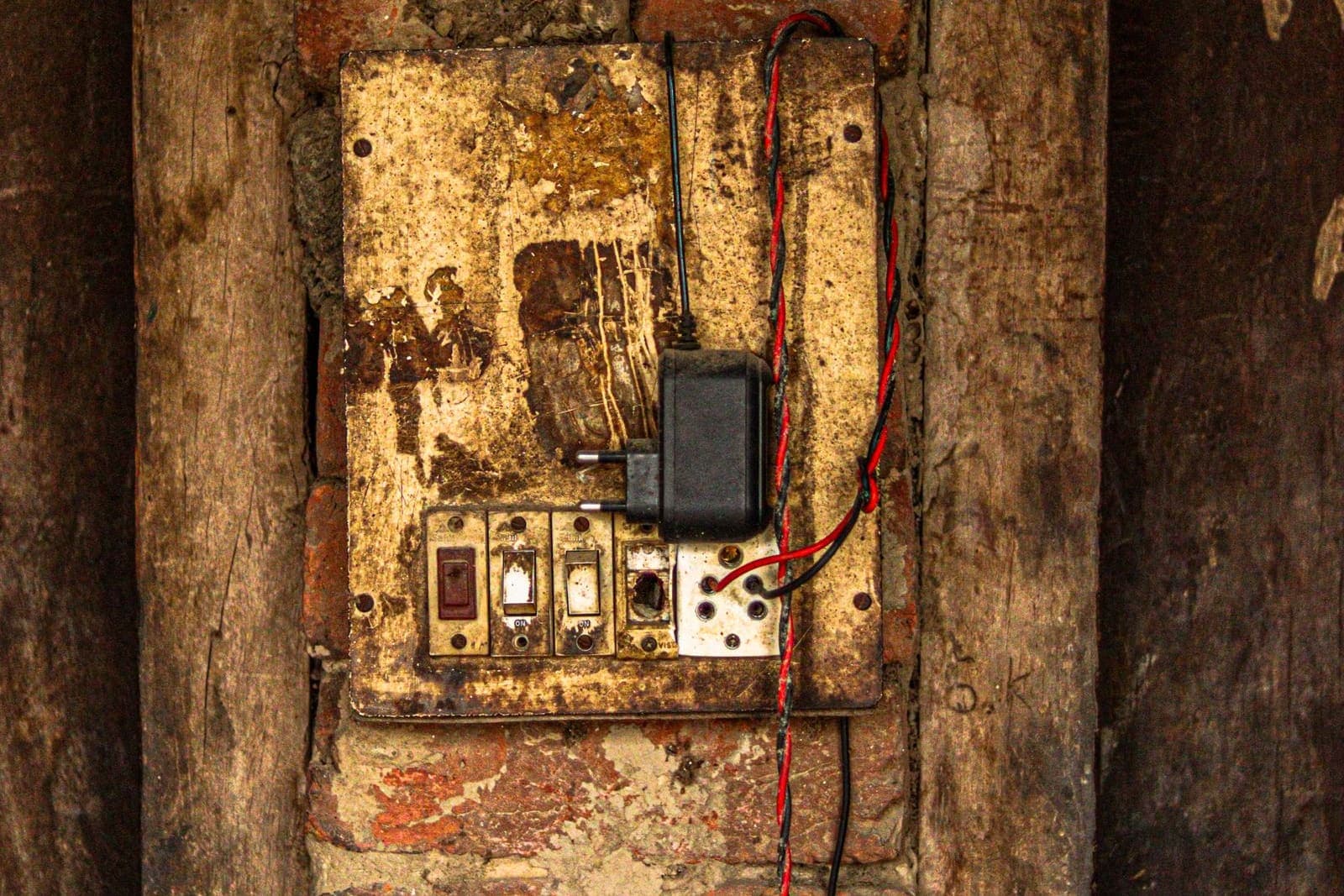 An old, rusted fuse box with exposed wiring